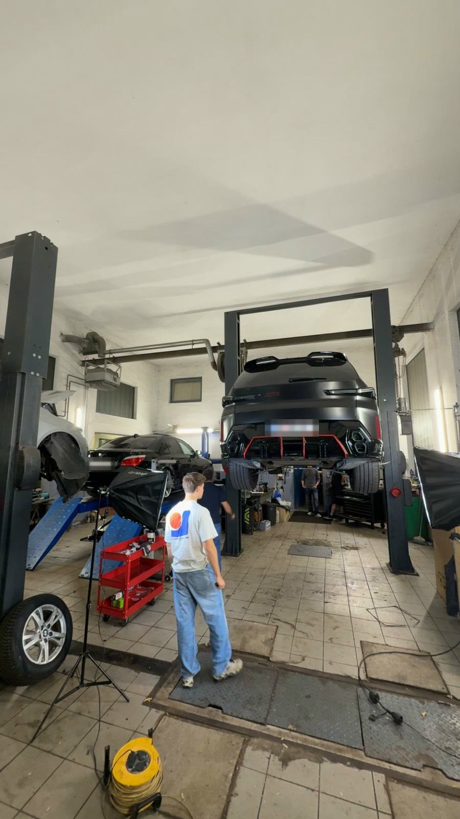 Werkstatthalle mit Fahrzeug auf der Hebebühne und Licht-Setup